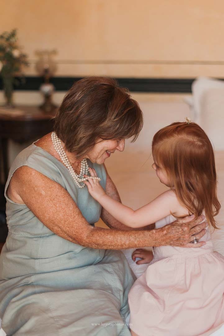 Granddaughter gently touching her grandmother’s pearl necklace during an intimate moment at a Lisbon micro-wedding.