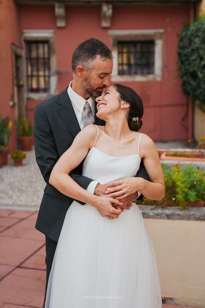 Bride and groom sharing smiles and hugs with family on a terrace in Lisbon after their intimate micro-wedding ceremony.