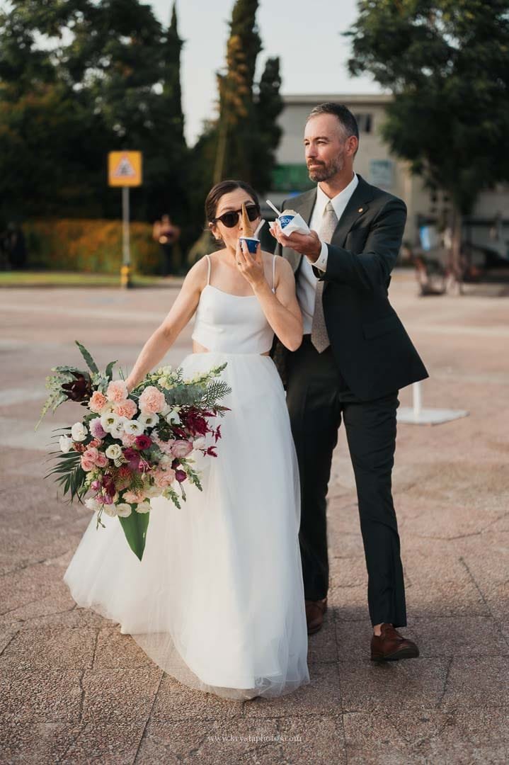Bride and groom sharing ice cream together before boarding a sailboat during their intimate Lisbon micro-wedding.