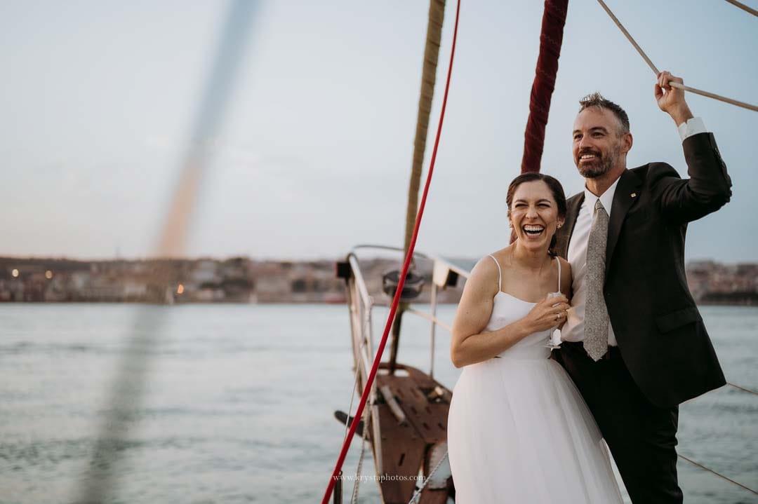Bride and groom enjoying a cheese and cold cuts board with bubbly on a sailboat during their sunset cruise in Lisbon.