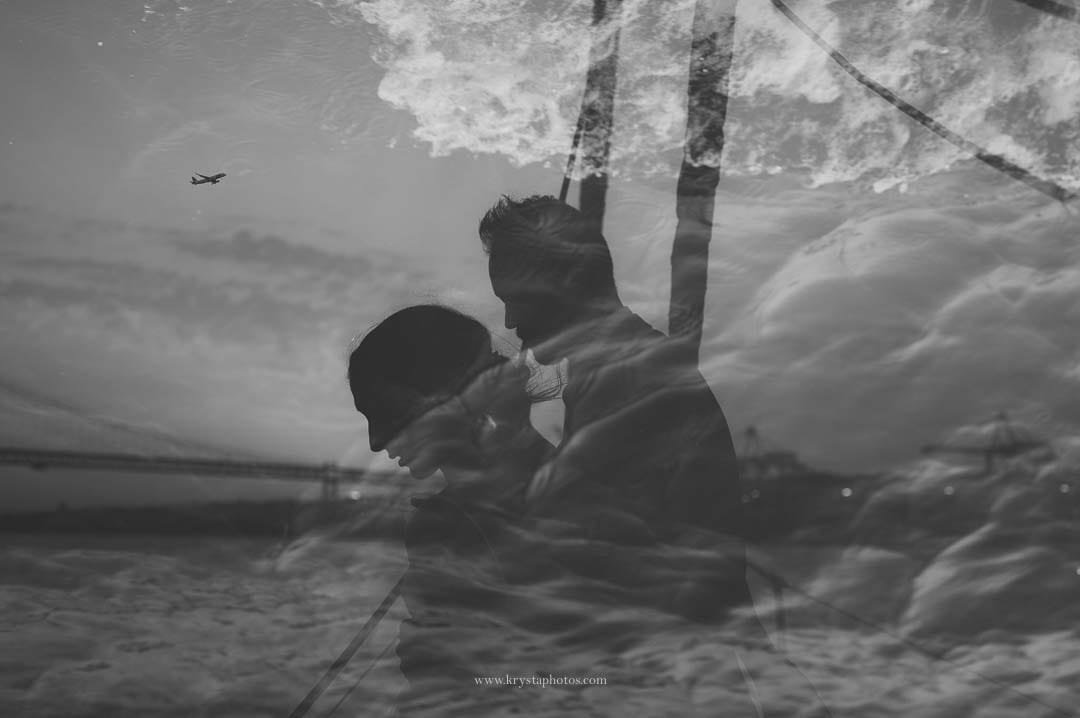 Sunset over the Tagus River in Lisbon with the bridge in view and a plane arriving, captured during an intimate micro-wedding sail.