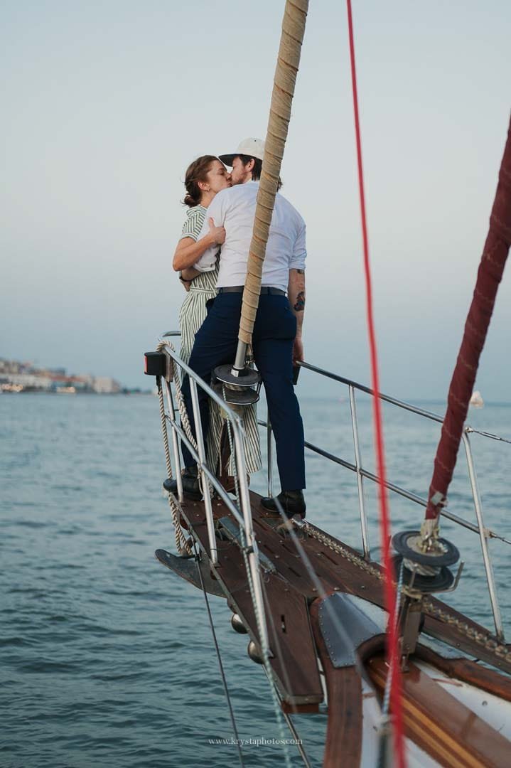 Bride and groom kissing on a sailboat during their sunset cruise in Lisbon after their intimate micro-wedding.