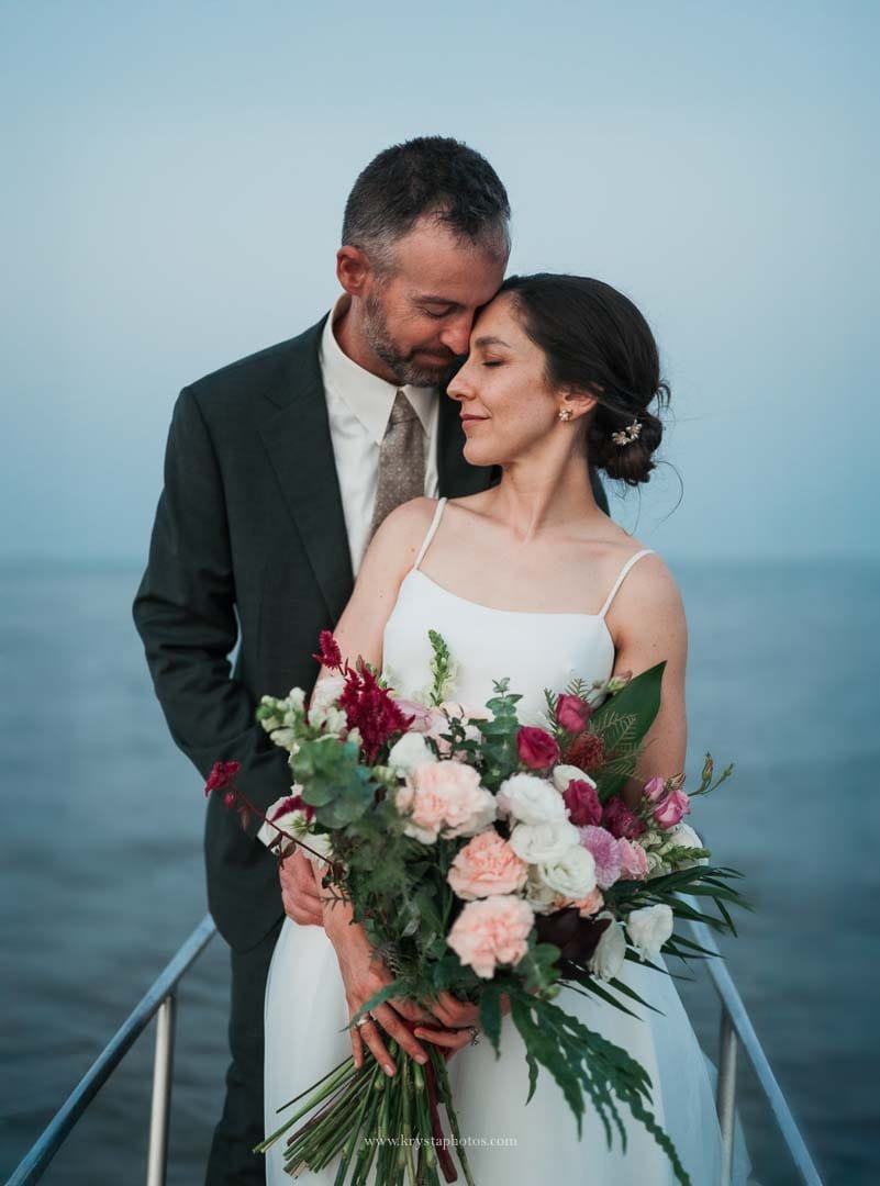 Bride and groom sharing an intimate portrait on a sailboat during blue hour in Lisbon after their micro-wedding.