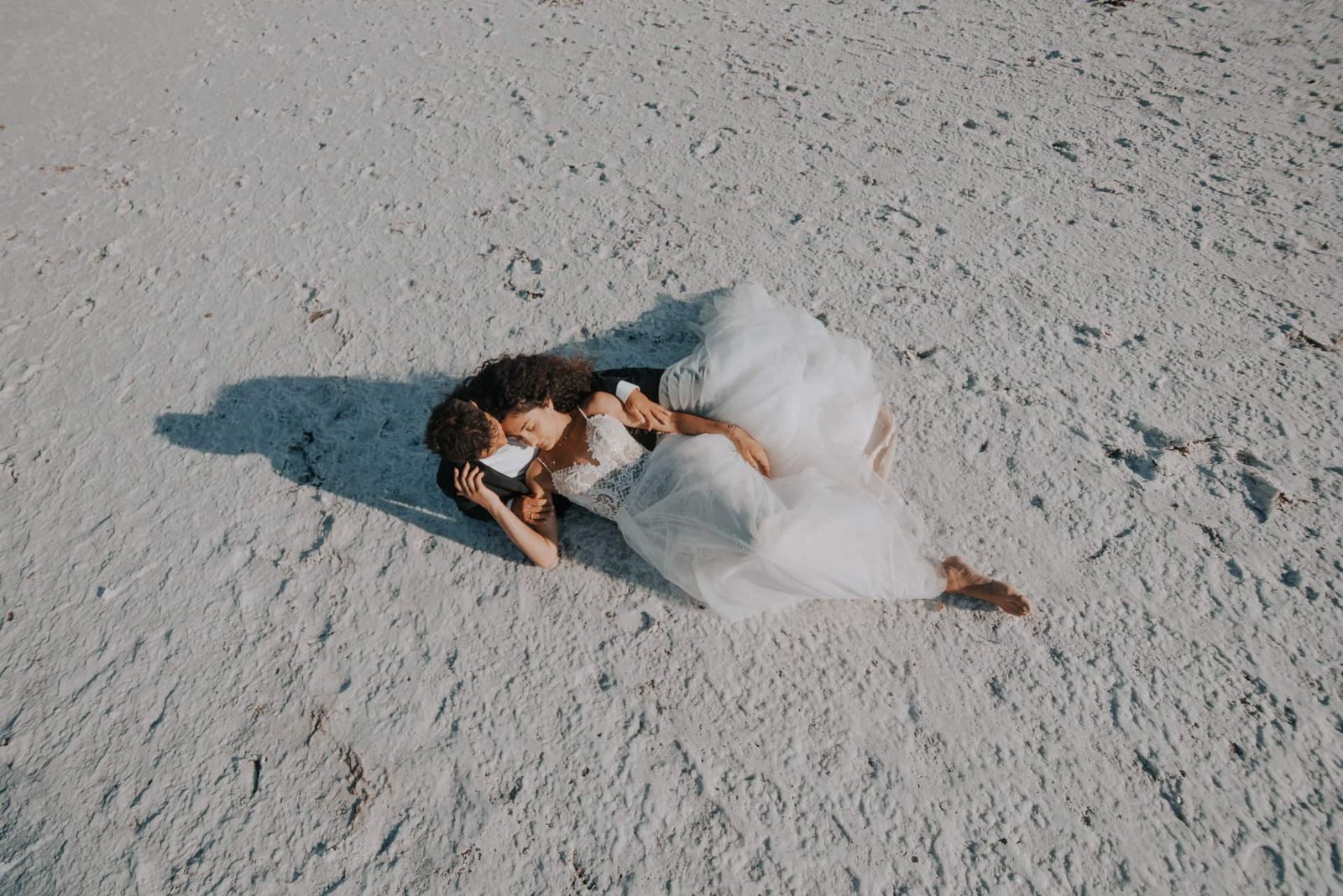 Bird's eye view of couple embracing and kissing on white salt flats, Greece destination wedding