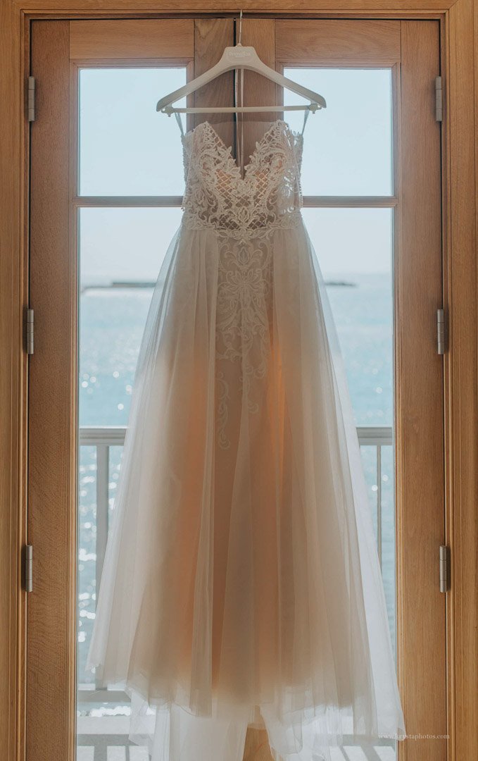 Pronovias wedding dress hanging by window with Aegean Sea view at Greek island destination wedding