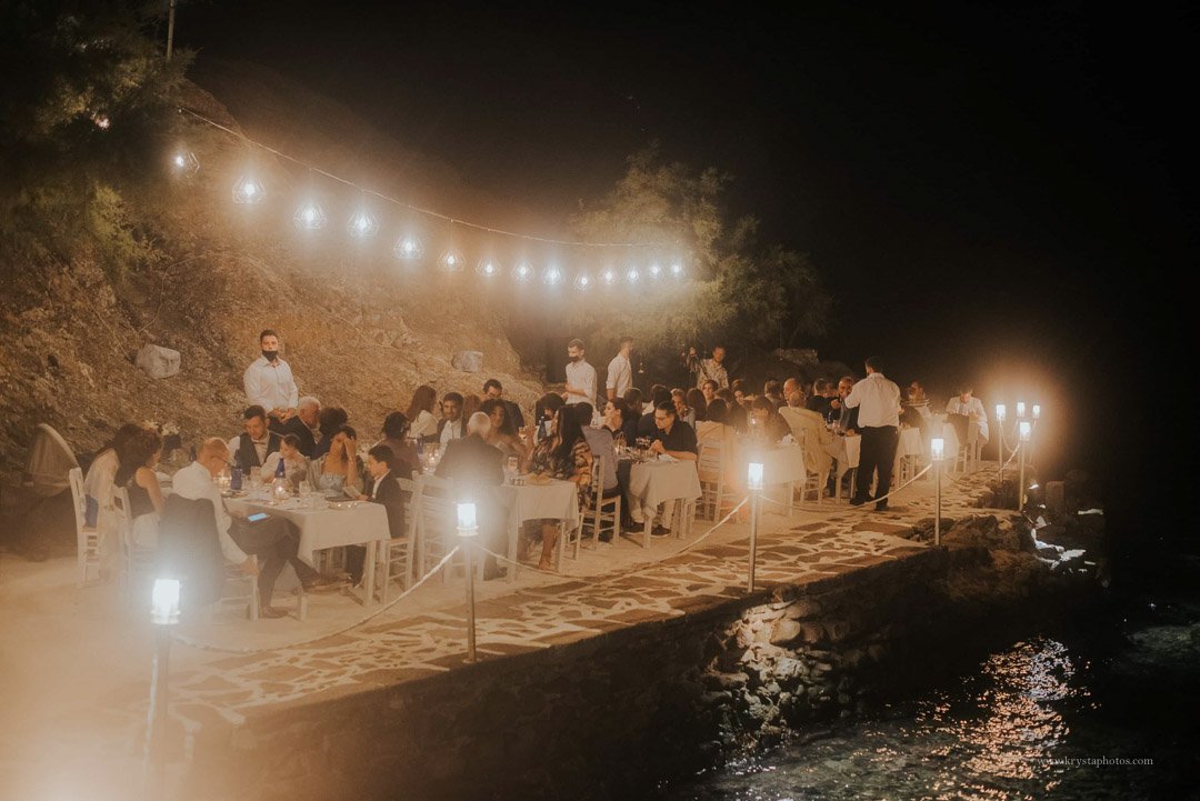 Candlelit seaside wedding dinner in Greece with newlyweds, guests, and live swing music by Gadjo Dilo