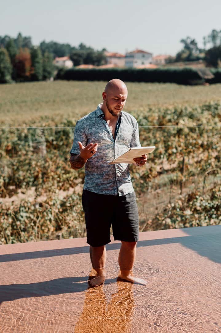 Groom rehearsing his vows and relaxing in a pool surrounded by lush green vineyards during a whimsical Portugal wedding