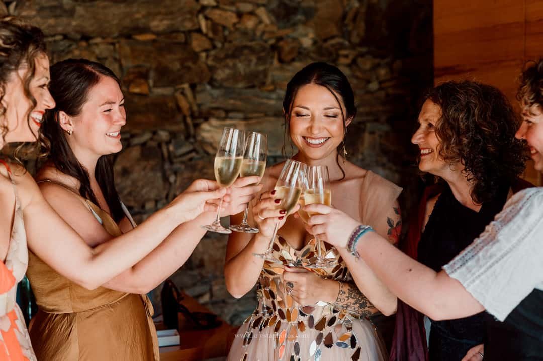 Bride in whimsical wedding dress toasting with bridesmaids and mom before Portugal vineyard ceremony