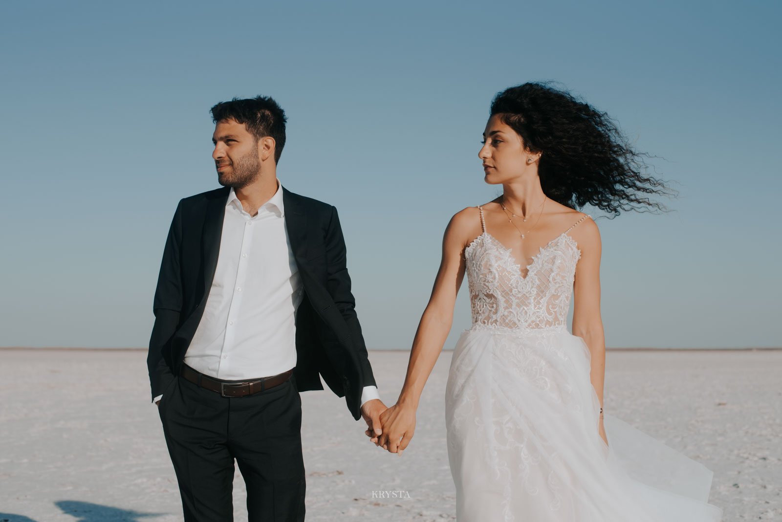 Bird's eye view of couple embracing and kissing on white salt flats, Greece destination wedding