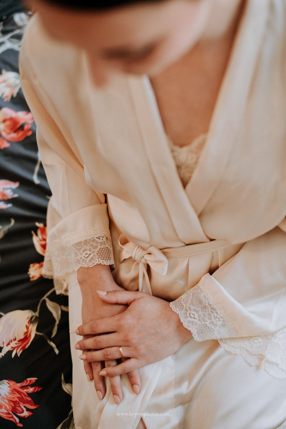 Bride wearing champagne silk robe with lace trim during bridal prep