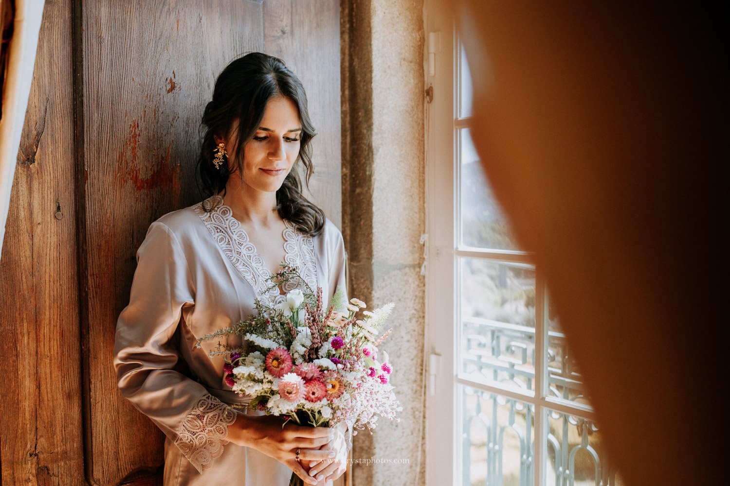 Bride wearing champagne silk robe during bride preparation for wedding
