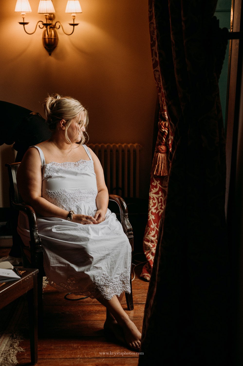 Bride wearing white silk robe with lace trim during bridal prep