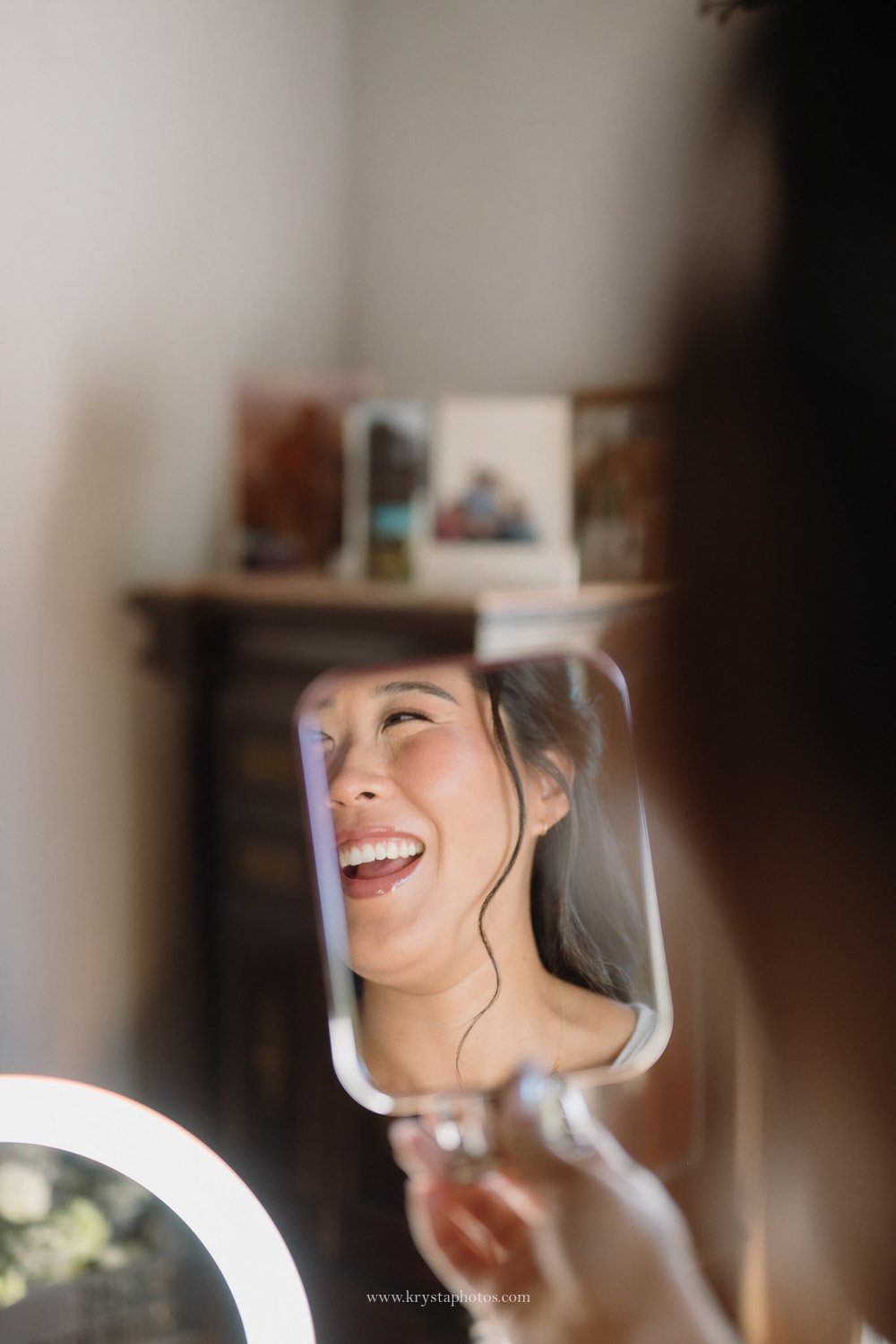 Bride smiling in mirror during bridal prep photos before her wedding