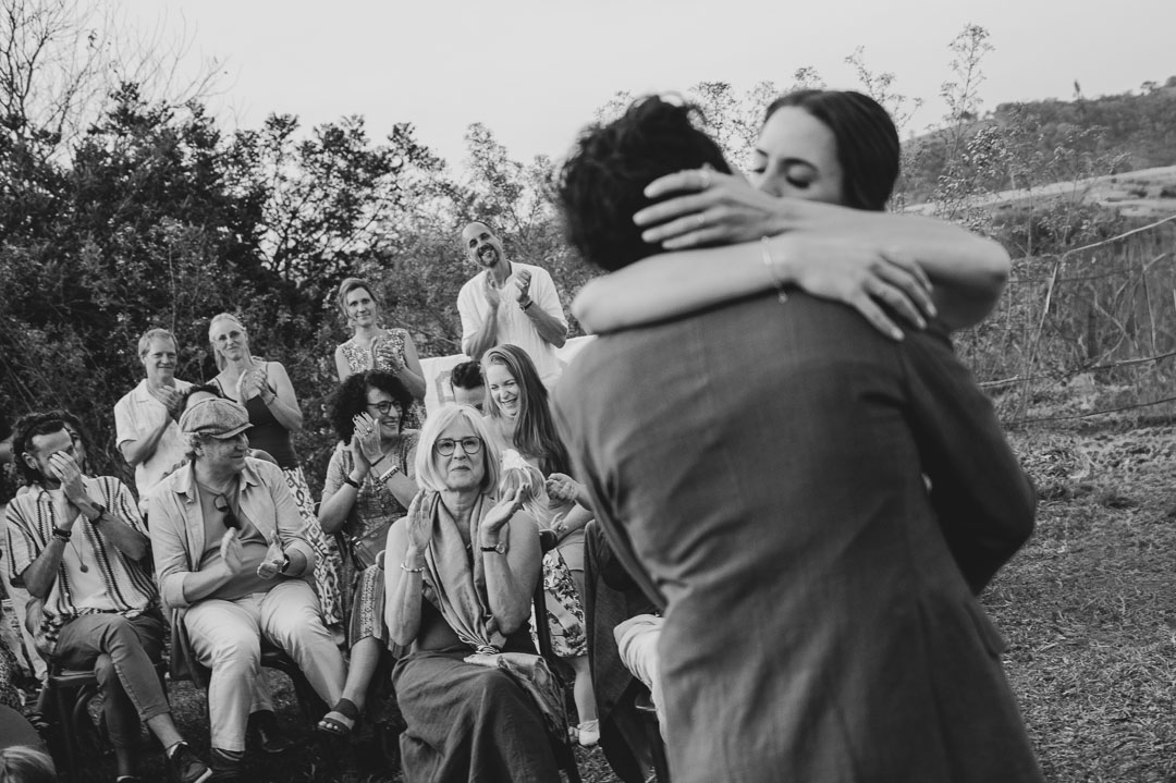 Bride and groom sharing their first kiss during an outdoor wedding ceremony in Portugal, surrounded by seated guests celebrating