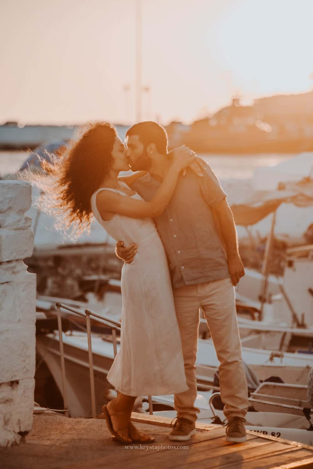 Couple kissing at sunset overlooking the whitewashed village of Myrina, Greece during a romantic engagement session