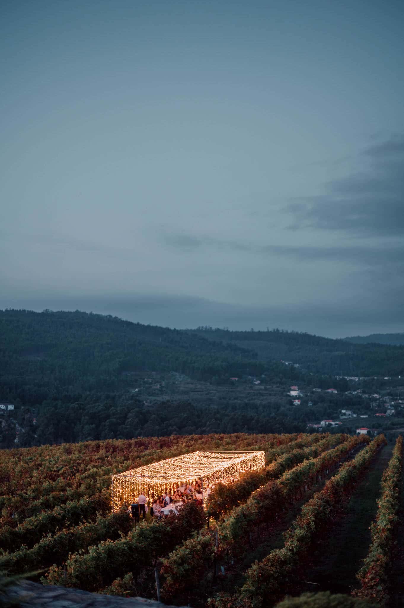Magical fairy light dinner setup surrounded by vineyards with glowing lightbulbs at a whimsical Portugal wedding