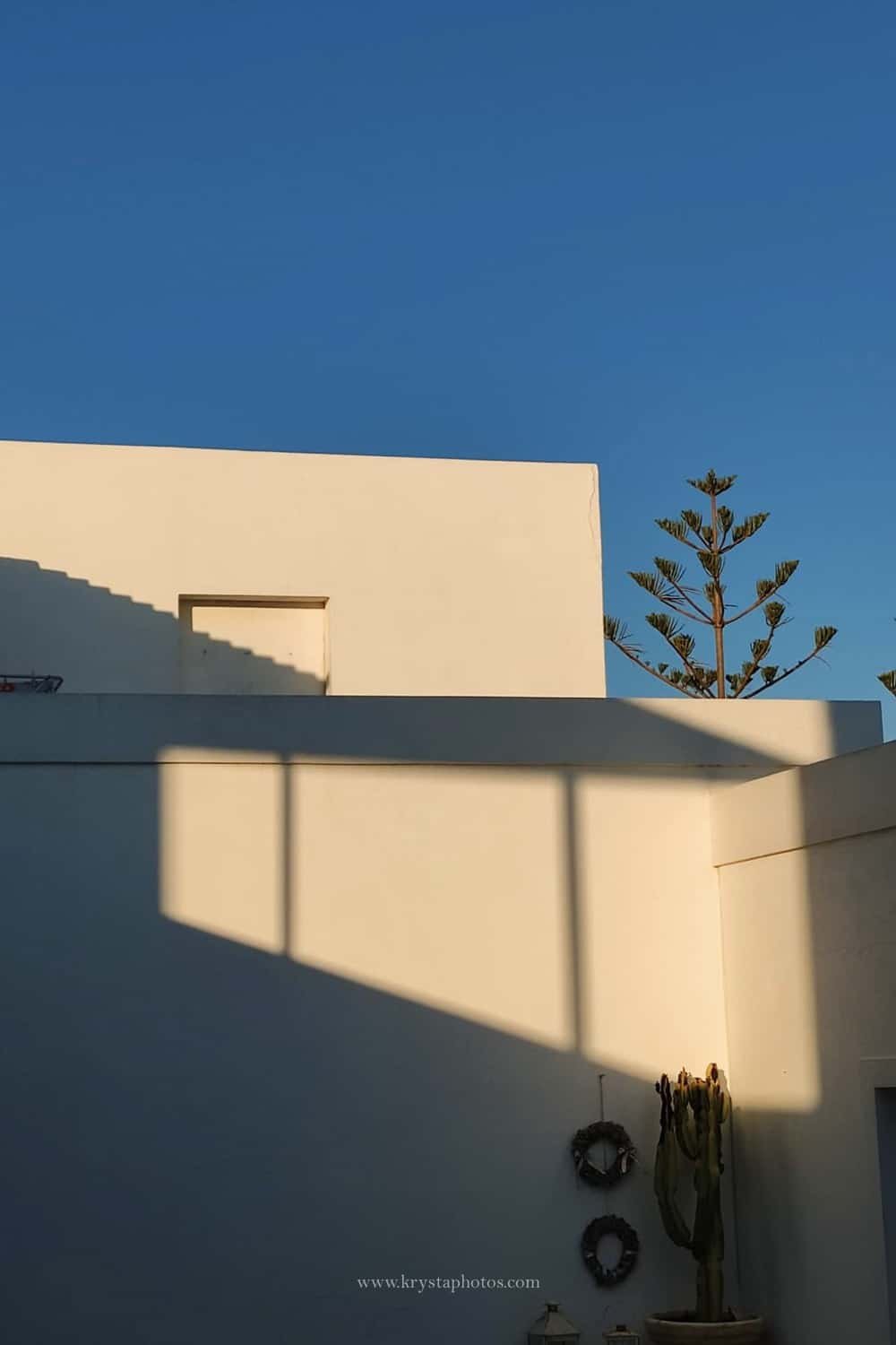 Couple kissing at sunset overlooking the whitewashed village of Myrina, Greece during a romantic engagement session