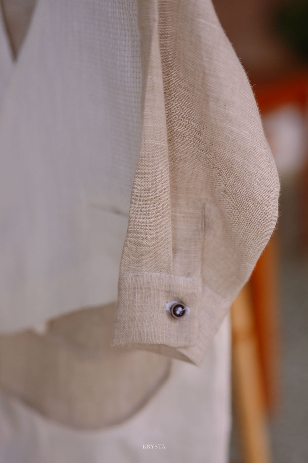 Cream linen and waffle-weave outfit by Designer's Cat hanging on a branded wooden hanger before a celebration in Limnos, Greece