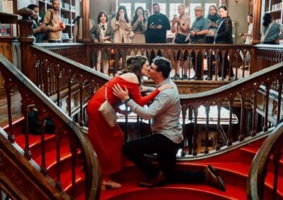 Marriage proposal on the iconic red staircase of Livraria Lello in Porto, Portugal, surrounded by tourists.